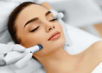 close up of woman laying down as dermatologist works with tool on her face