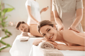 Romantic young couple enjoying back massage in spa salon